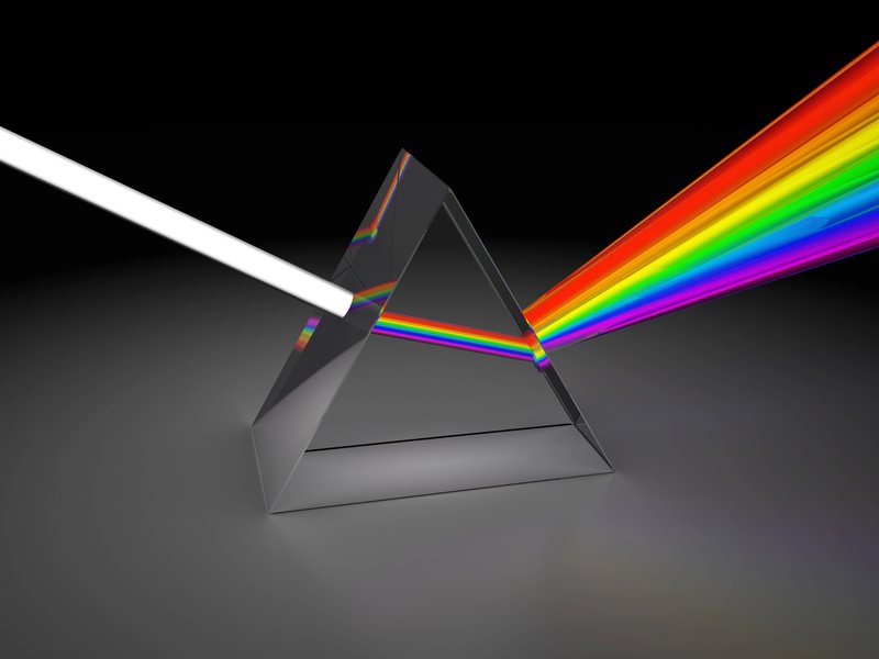 A glass prism dispersing a beam of white light into a spectrum of rainbow colors on a dark background, symbolizing how breaking down knowledge into multiple dimensions leads to deeper and more nuanced understanding.